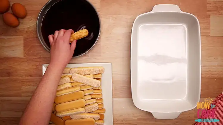 Dipping ladyfingers savoiardi for making tiramisu